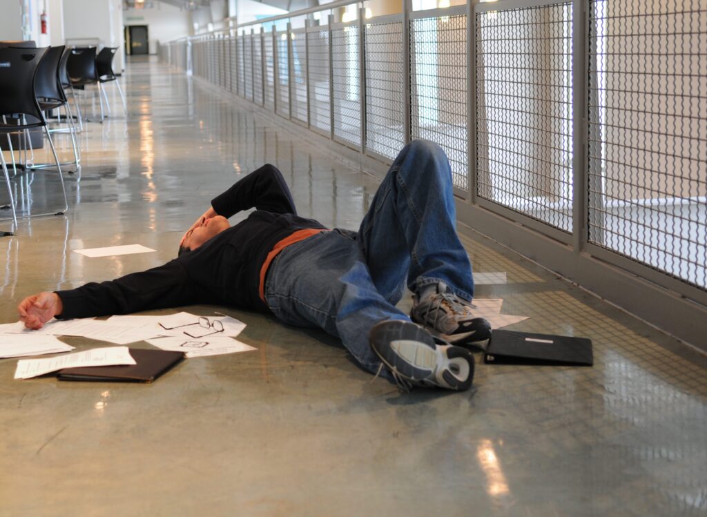 An image of a distressed man with papers around him while he is on the floor after a slip and fall.