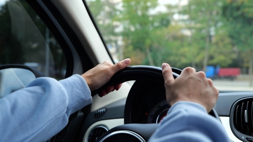 Hands gripping steering wheel inside car during driving scene
