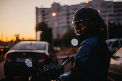 female motorcyclist riding motorcycle on city street wearing helmet and jacket