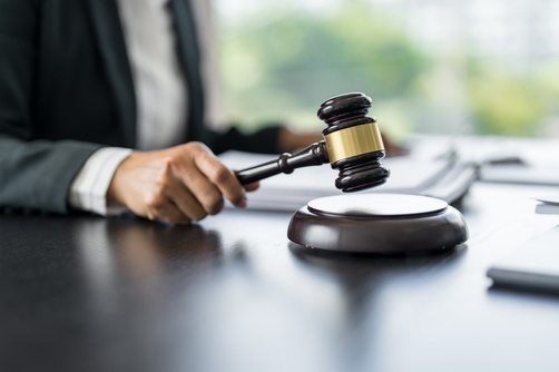 suited professional striking gavel on sound block at legal desk
